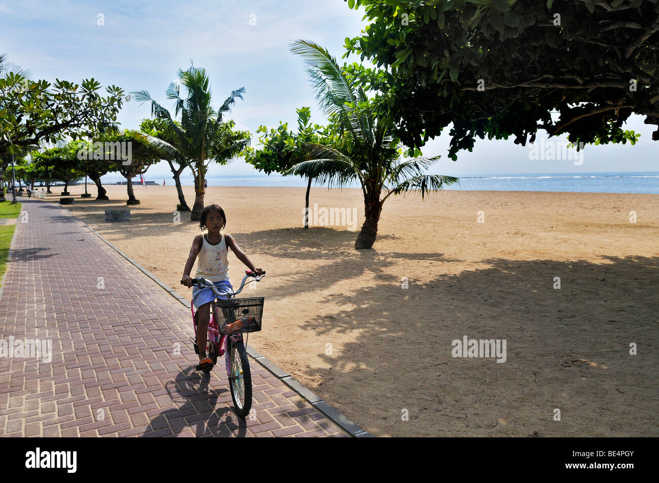 Spiaggia con alberi e ciclista vicino a Sanur Denpasar, Bali, Indonesia, sud-est asiatico Foto Stock