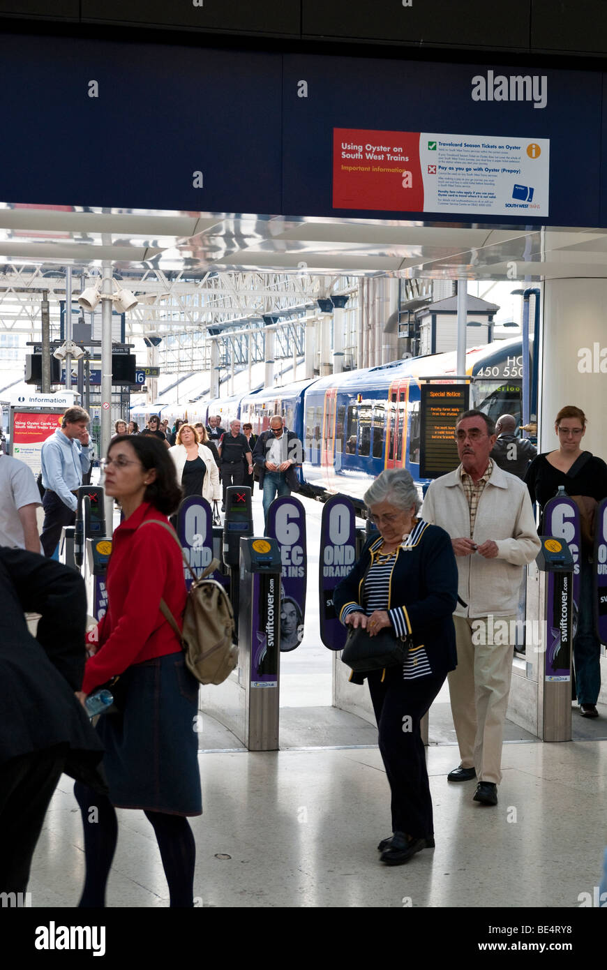 Passeggero in partenza attraverso la porta di uscita alla stazione ferroviaria di Waterloo Foto Stock