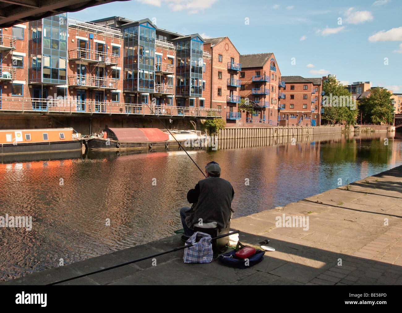Pescatore e il fiume Aire a Leeds Regno Unito con appartamenti e longboats Foto Stock