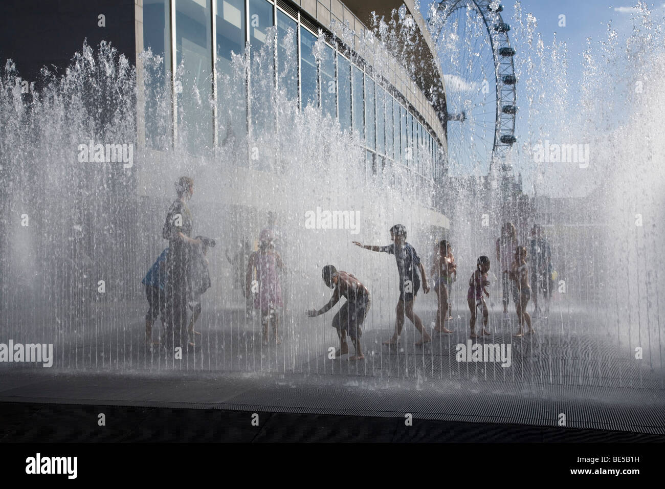 Bambini che giocano in acqua impianto di gioco, Southbank sul fiume Tamigi vicino alla Hayward Gallery. Calda serata estiva. London Eye background Foto Stock