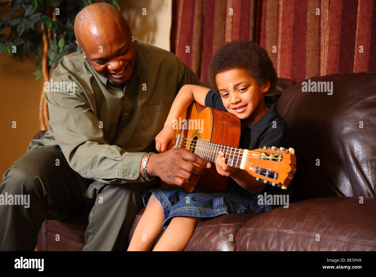 Padre figlio di insegnare a suonare la chitarra Foto Stock