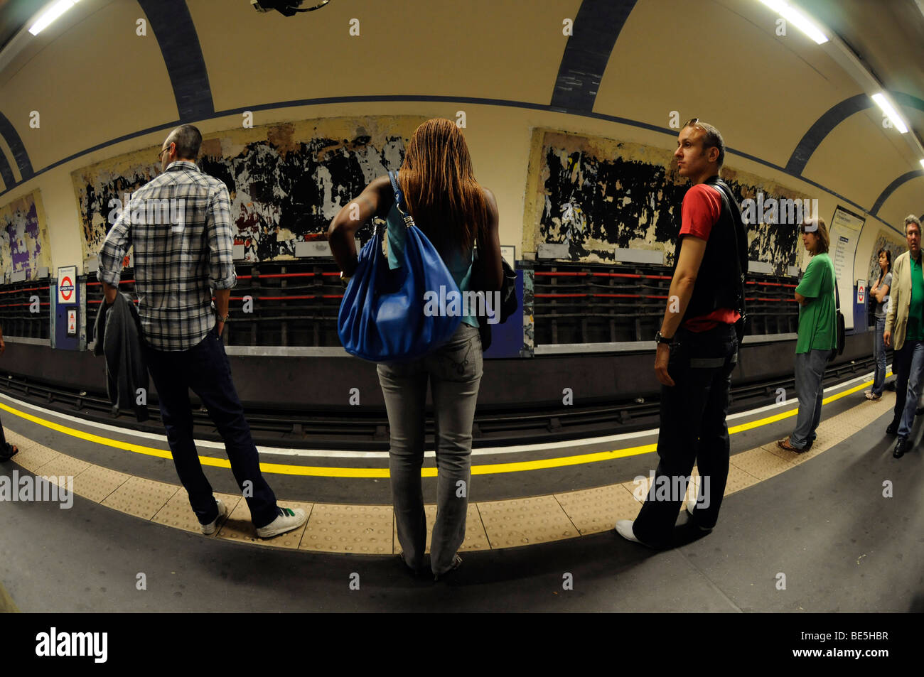 La donna in attesa con altri pendolari per un tubo il treno per arrivare a una stazione della metropolitana piattaforma in Londra. Foto Stock