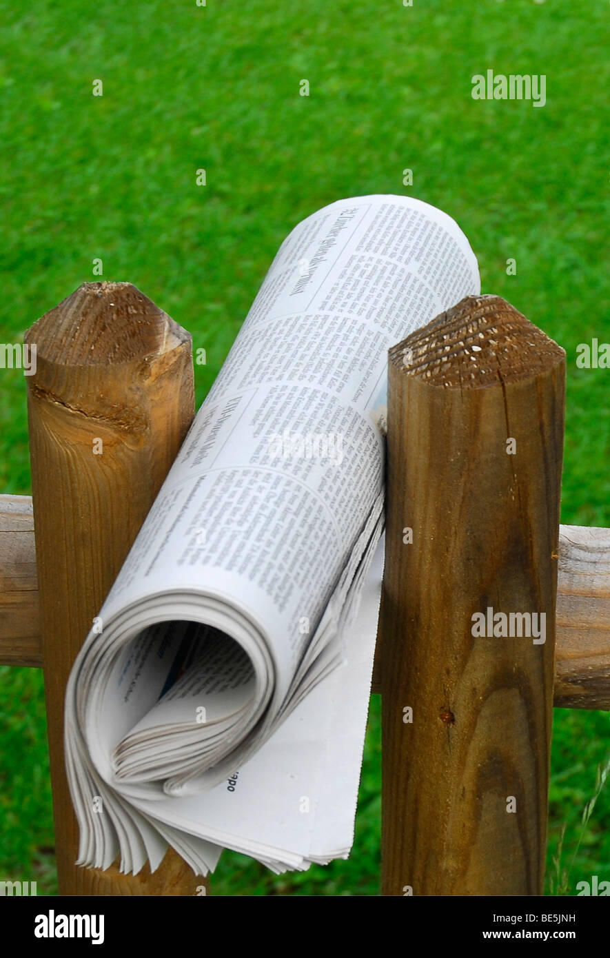 Giornale arrotolato tra due fenceposts Foto Stock
