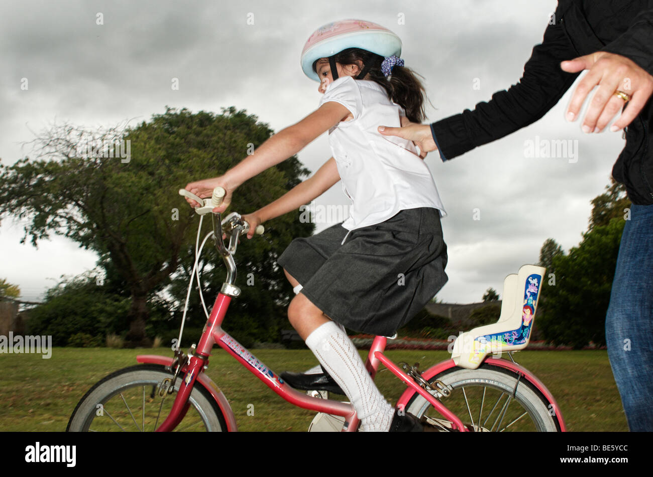 Genitore aiutare il bambino ad imparare una bicicletta Foto Stock