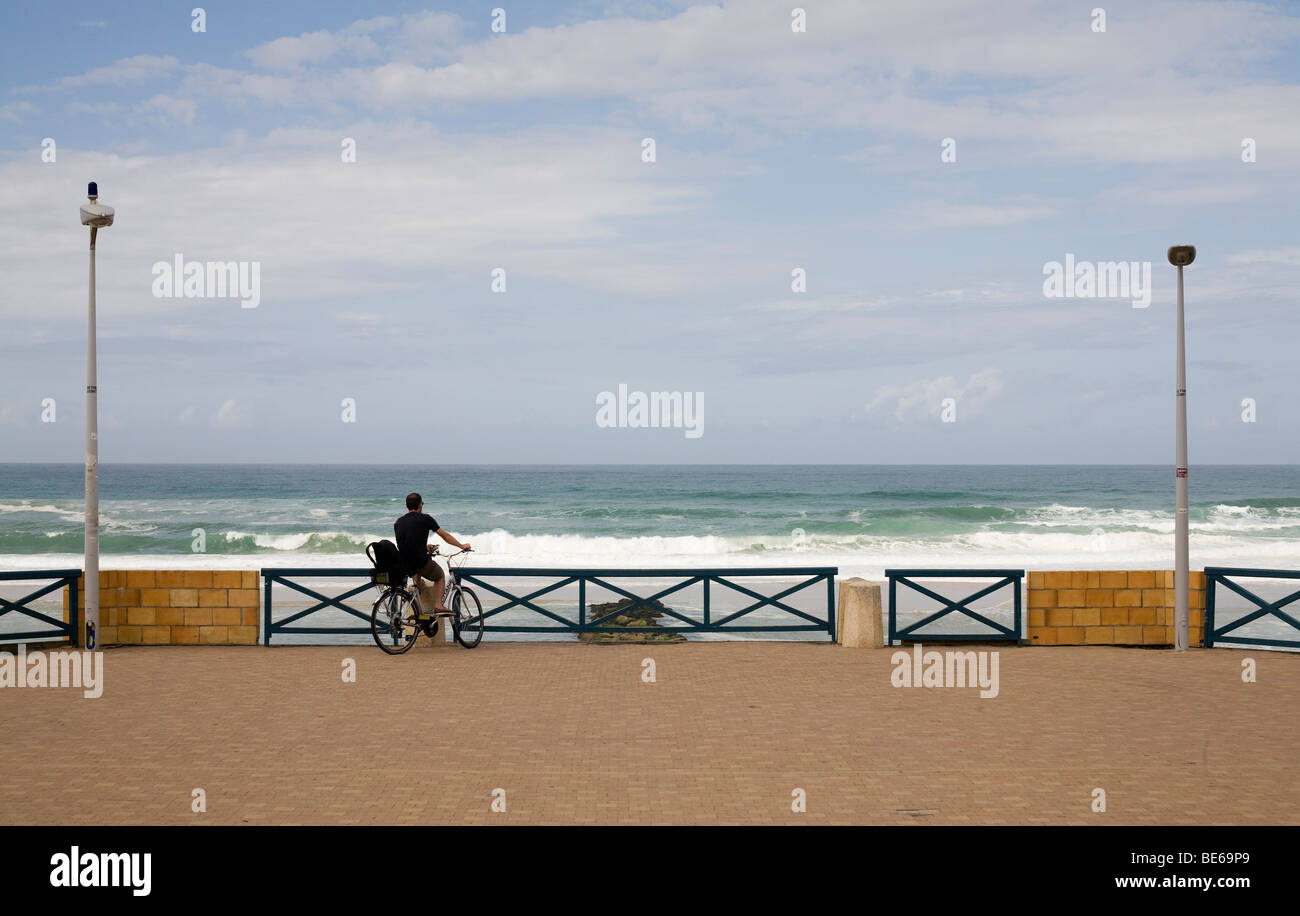 Un ciclista guarda all'oceano atlantico di fronte al mare a Lacanau Ocean sulla costa vicino a Bordeaux in Francia Foto Stock