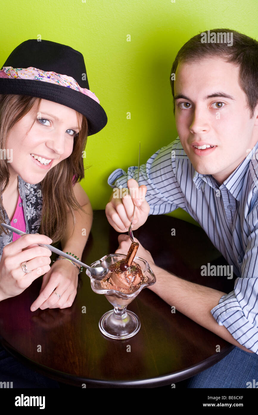 Due i giovani alla moda la condivisione di un gelato al cioccolato con un fiocco in un fresco cafe. Foto Stock