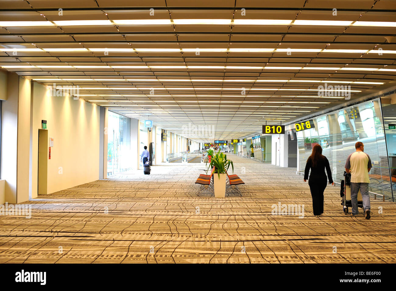 Passeggeri a piedi attraverso la zona di attesa passato cancelli d'imbarco, l'Aeroporto Internazionale di Singapore Changi, Singapore, Asia Foto Stock