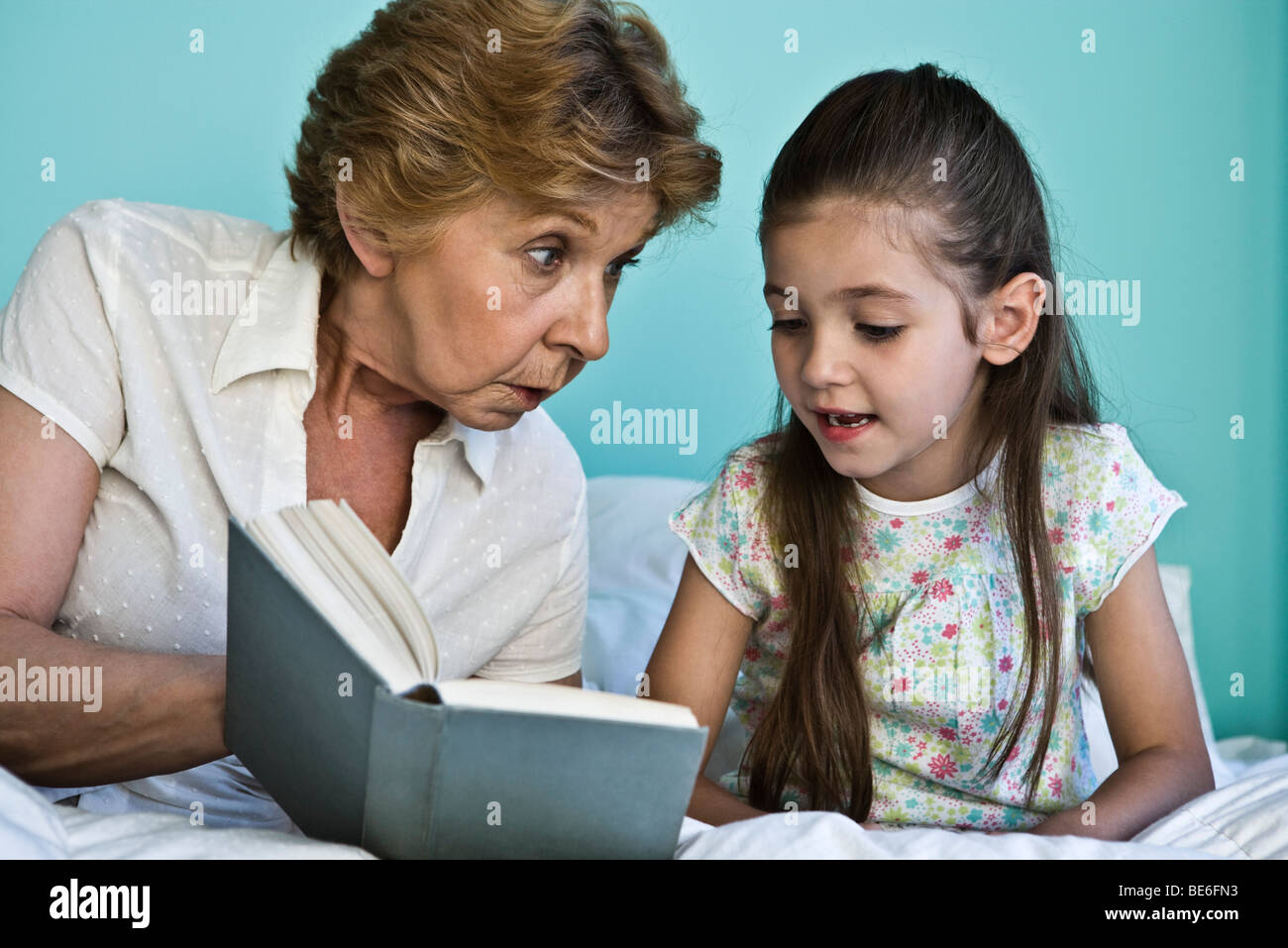 Bambina libro di lettura con la nonna Foto Stock