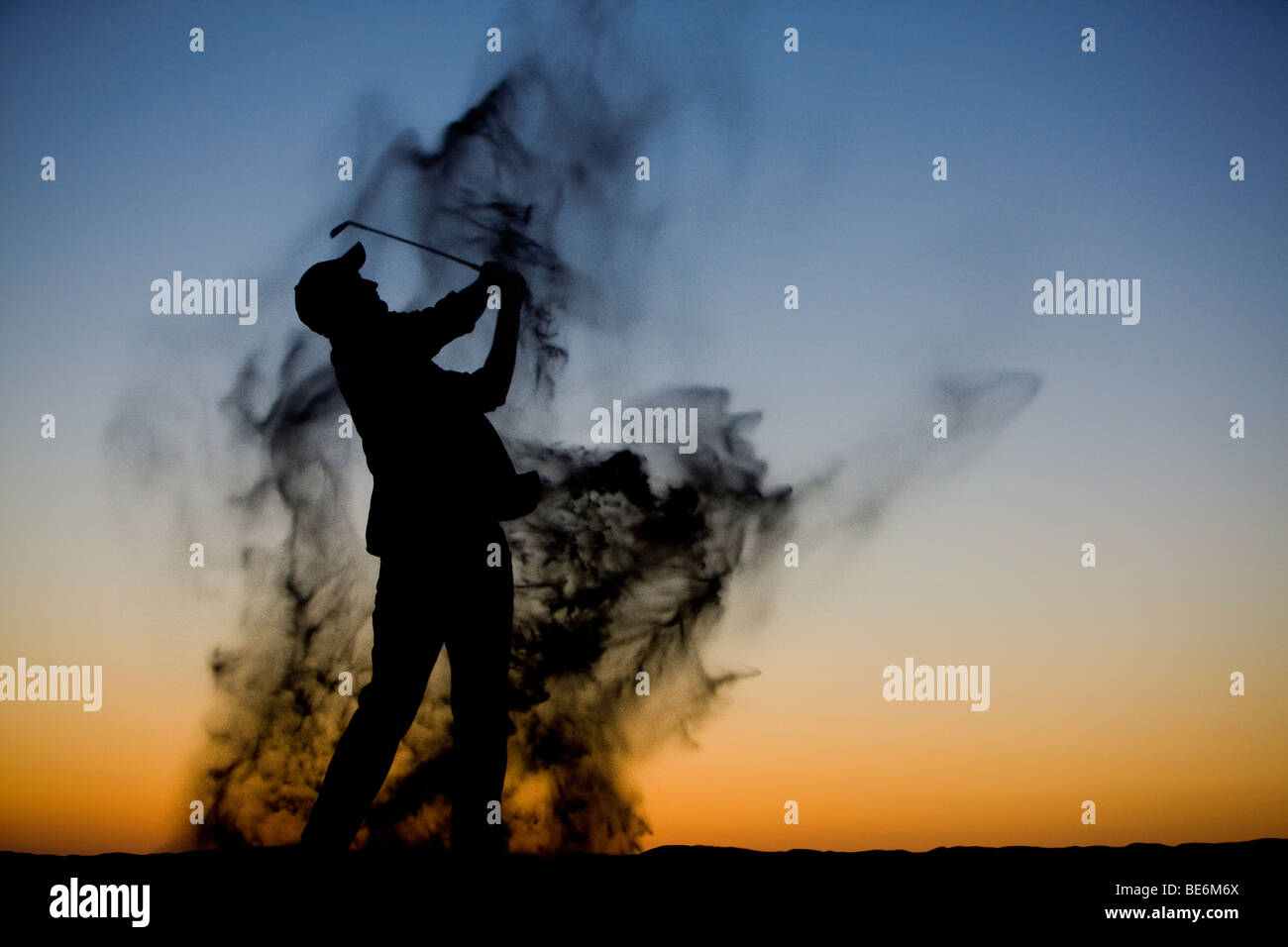 Silhouette di un golfista a fine giornata come egli oscilla attraverso una trappola di sabbia Foto Stock