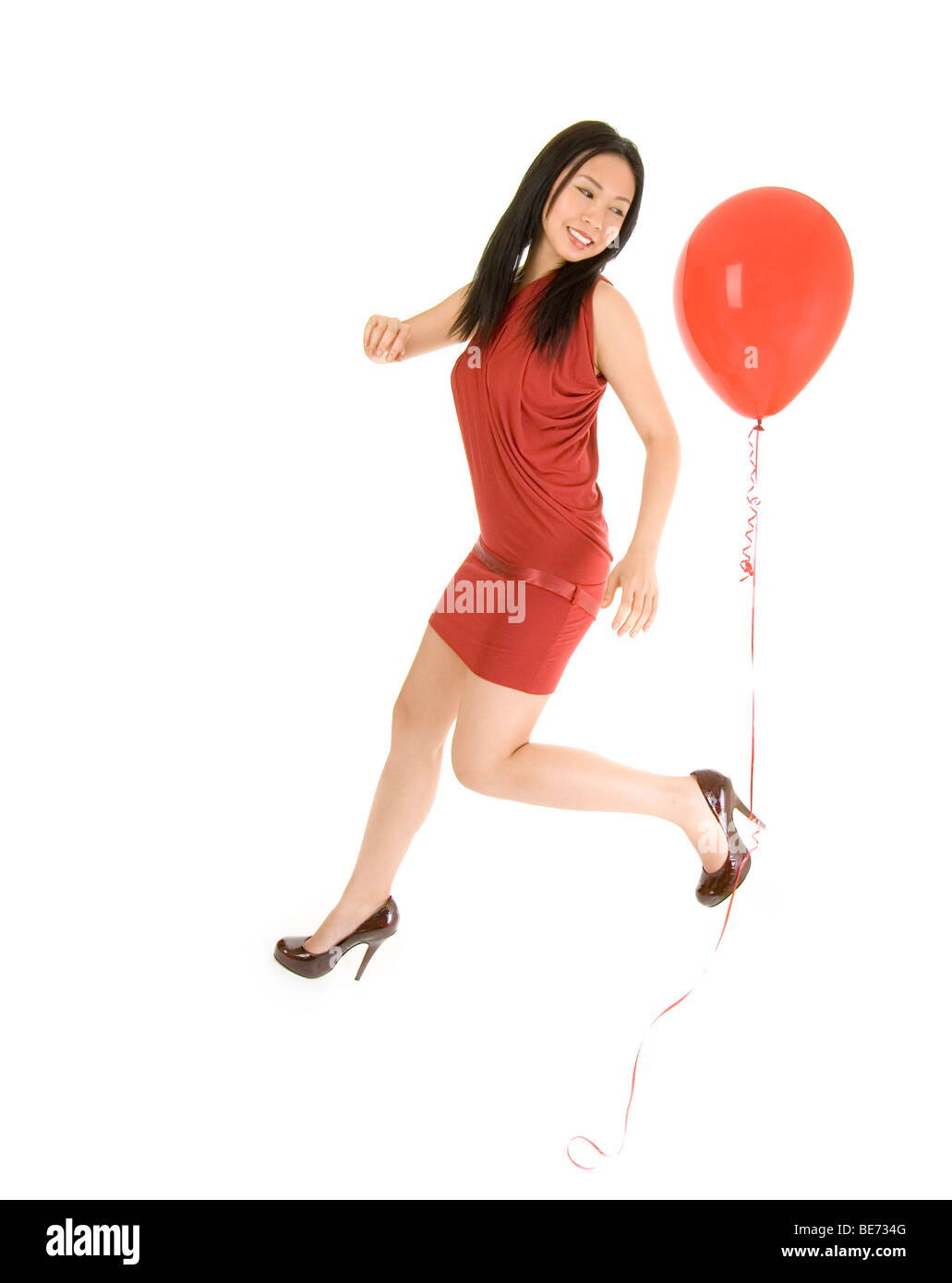 Ragazza che corre con palloncino rosso legato al tallone Foto Stock