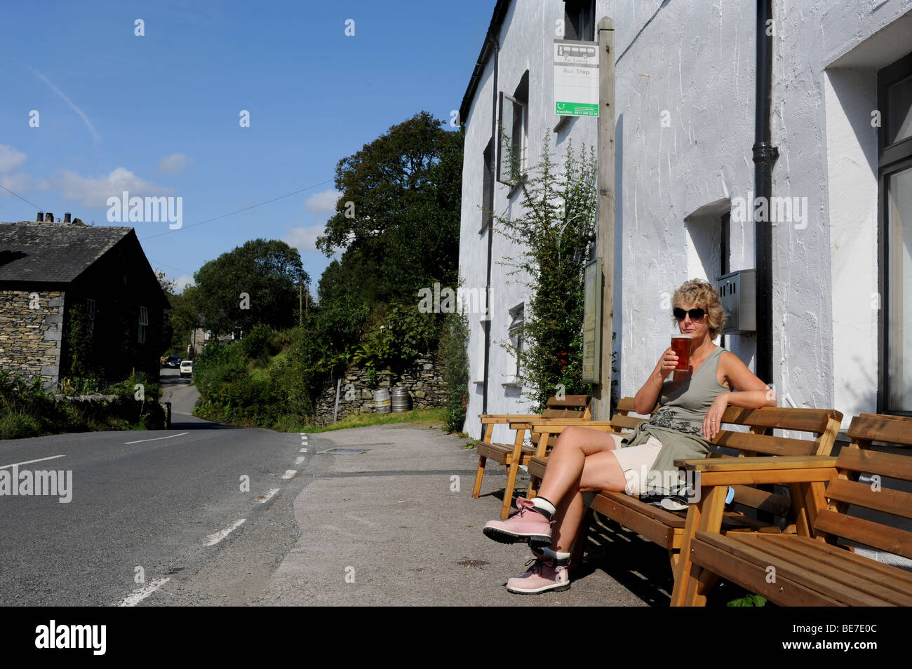 Il camminatore femmina gode di una pinta di birra in un pub in remoto a lontano Sawrey nel Lake District Cumbria Regno Unito Foto Stock
