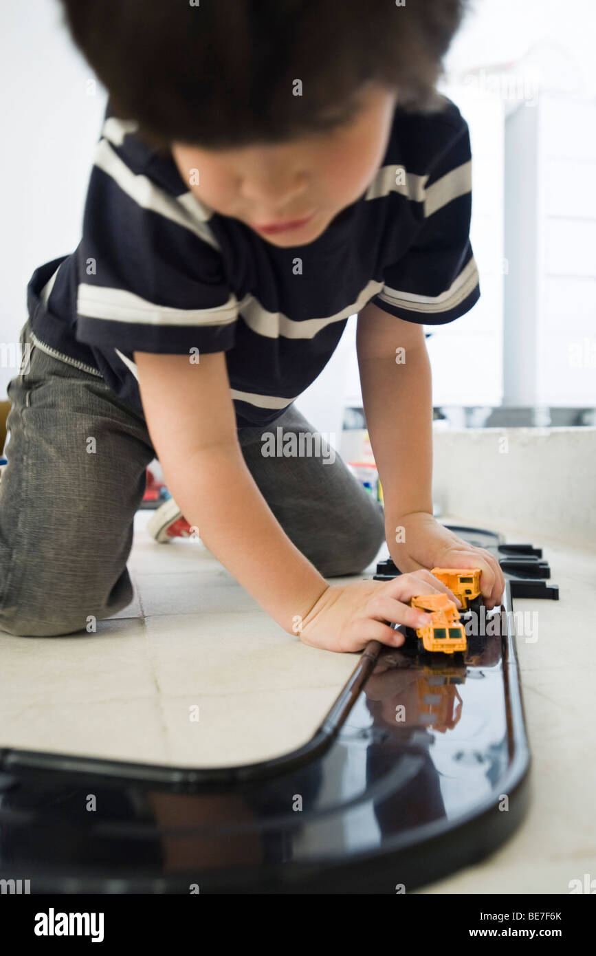 Little Boy giocando con le vetture in pista in plastica Foto Stock