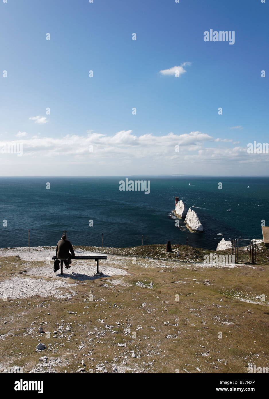 Un prestito uomo si siede e guarda gli aghi sull'Isola di Wight Foto Stock