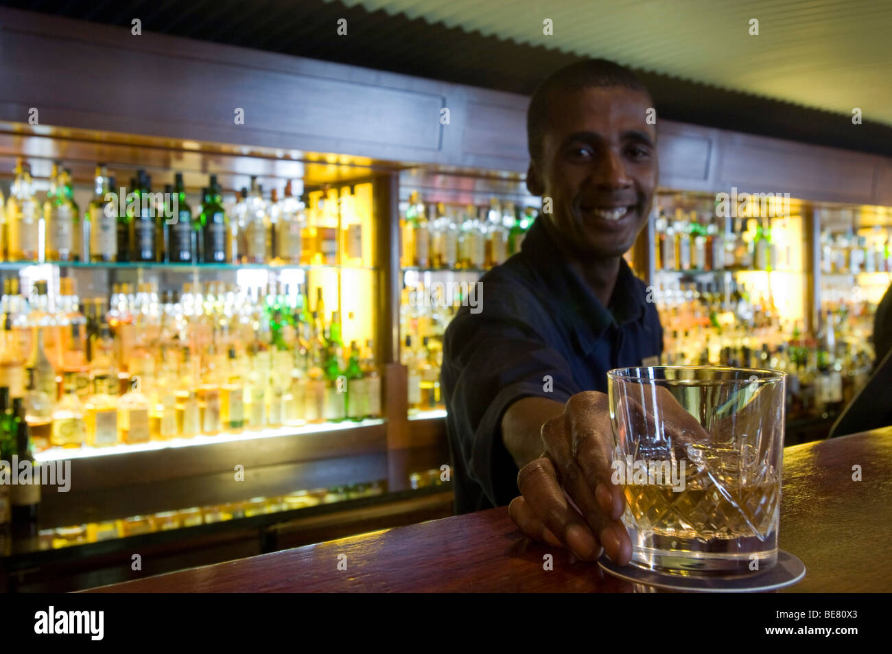 Barman sorridenti che serve un bicchiere di whiskey, Barra basculante, Cape Grace Hotel Cape Town, Sud Africa e Africa Foto Stock