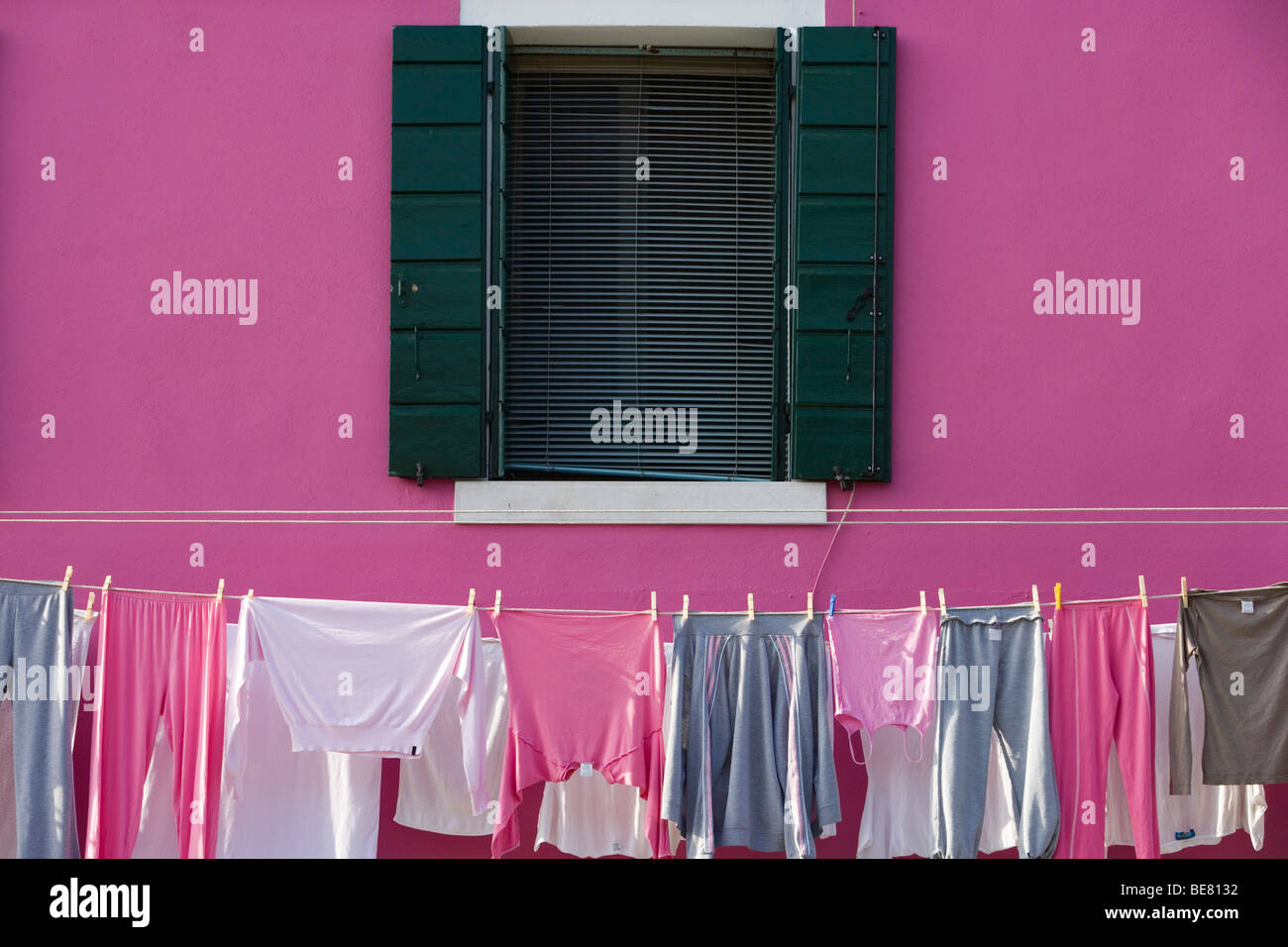 Rosa e grigio l'asciugatura di biancheria in una linea di lavaggio al di fuori di un dipinto di rosa house, Burano, Veneto, Italia Foto Stock