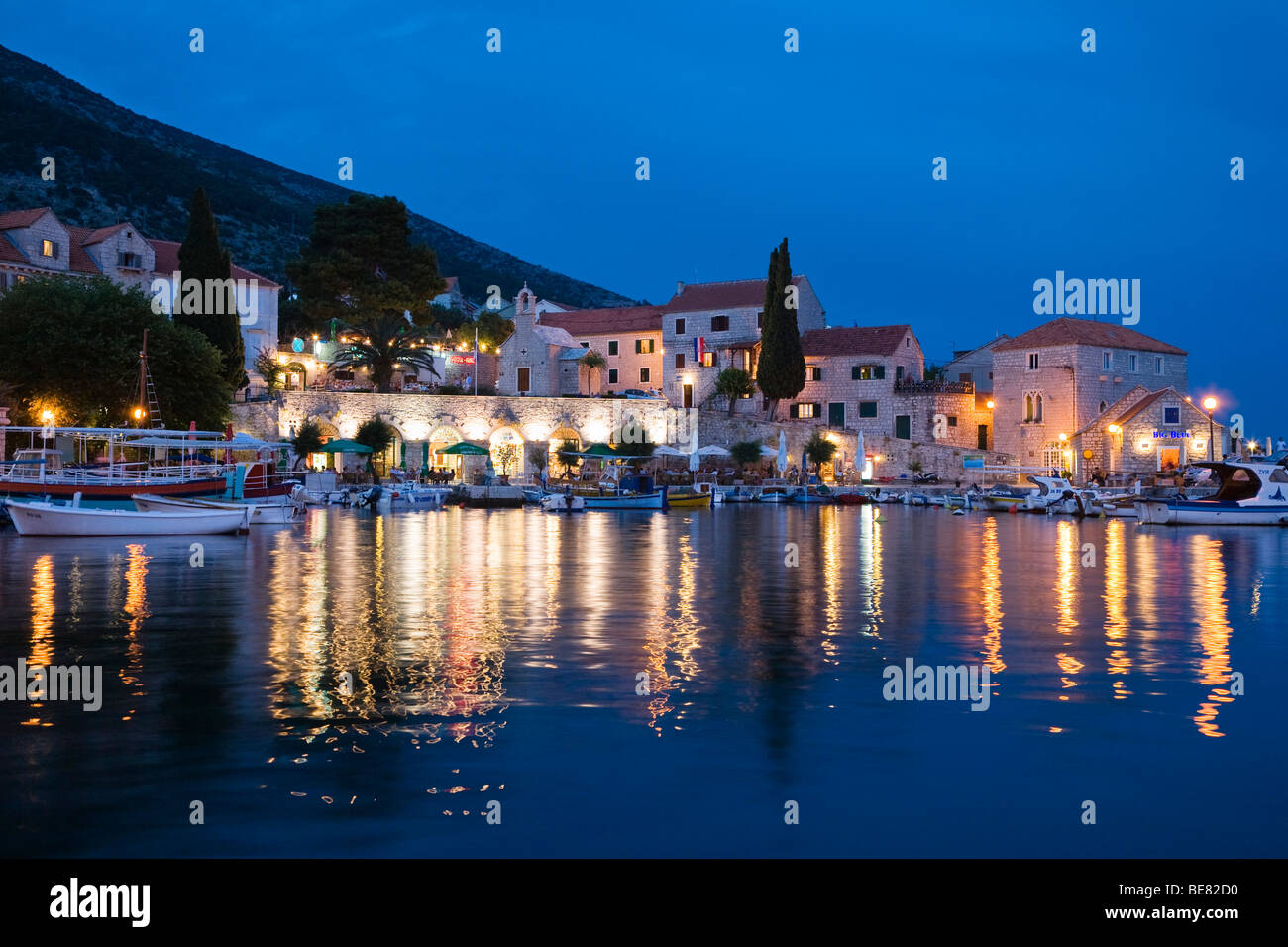 Case illuminate a Bol in porto la sera, Isola di Brac, Dalmazia, Croazia, Europa Foto Stock