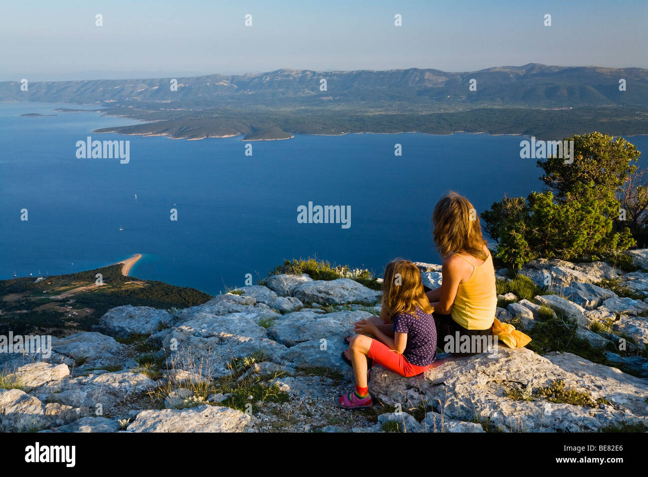La madre e il bambino seduto sulle rocce nella luce del tramonto, Vidovica, Vidova Gora, Isola di Brac, Dalmazia, Croazia, Europa Foto Stock
