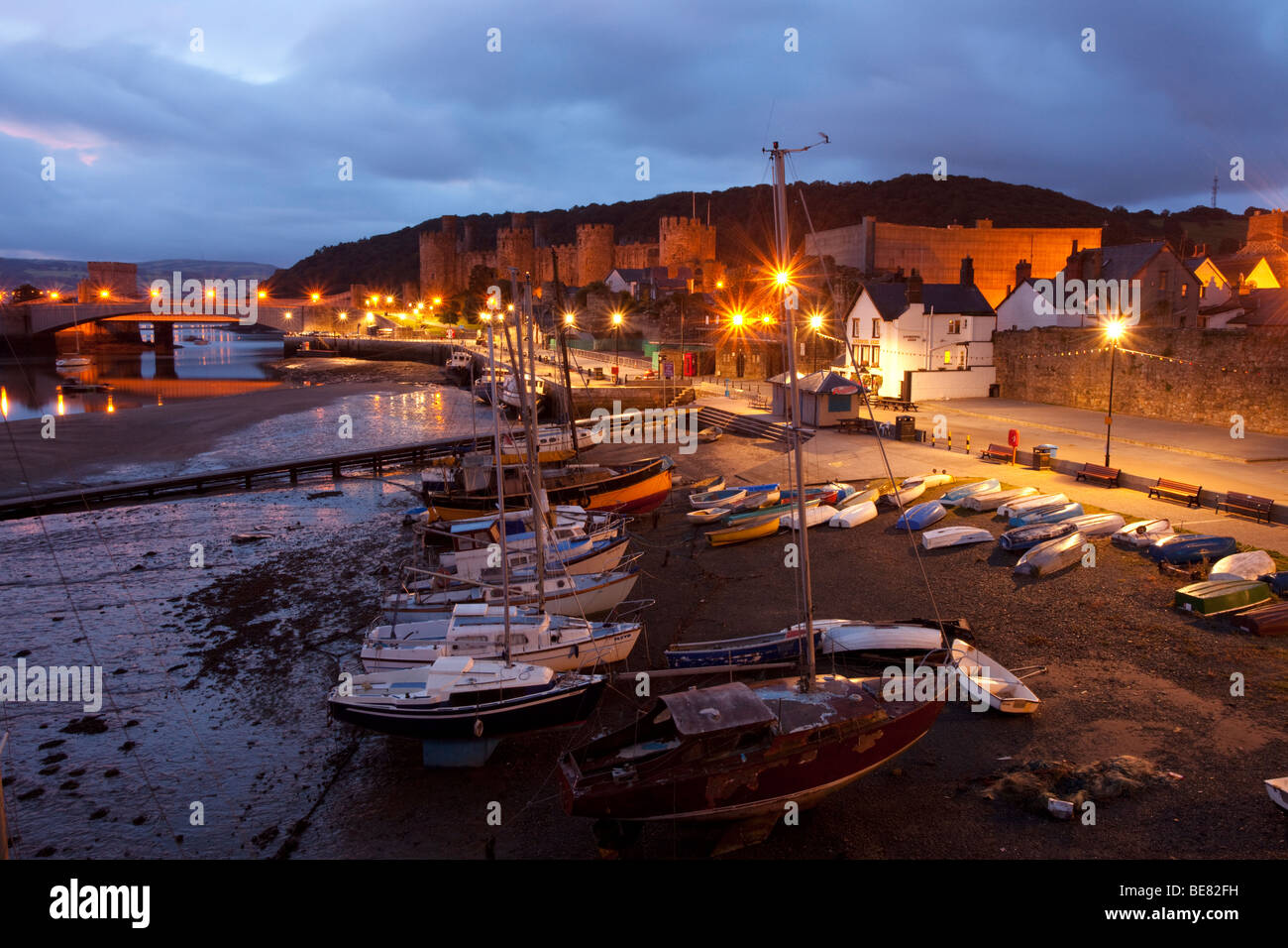 Conwy harbour scena prima la luce del mattino, con i lampioni che splende su barche e Jetty. Foto Stock
