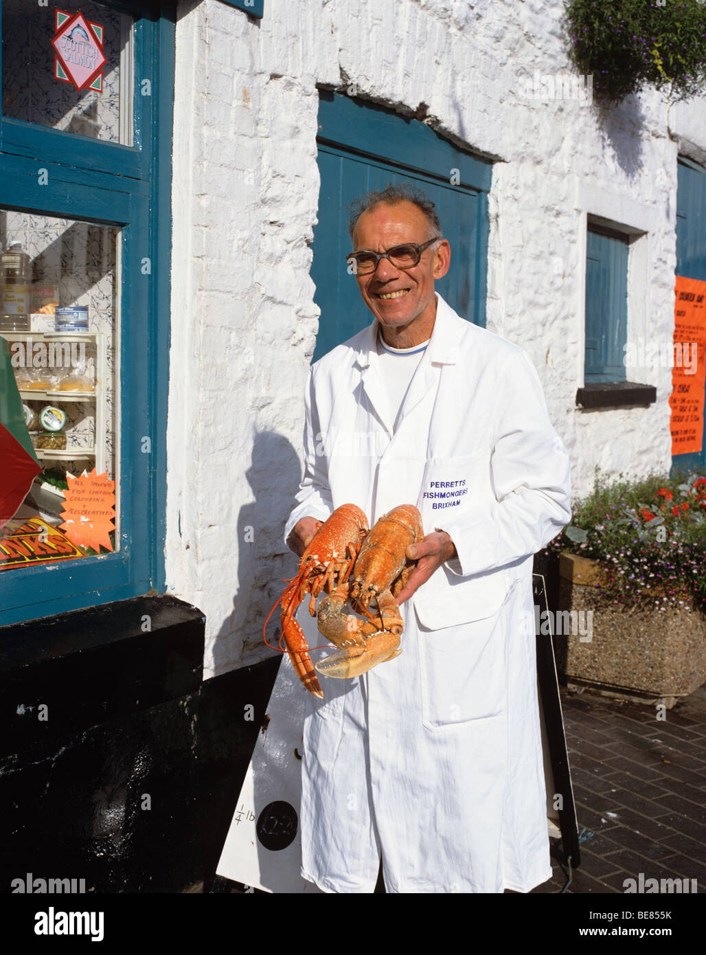 Pescivendolo locale con prodotti locali freschi scampi in vendita nel famoso porto di pesca e frequentata stazione balneare di Brixham Foto Stock