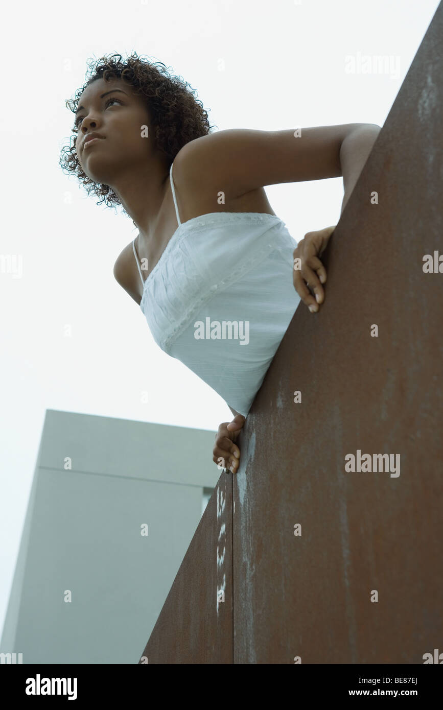 Giovane donna sul balcone, sporgersi, guardando lontano, a basso angolo di visione Foto Stock