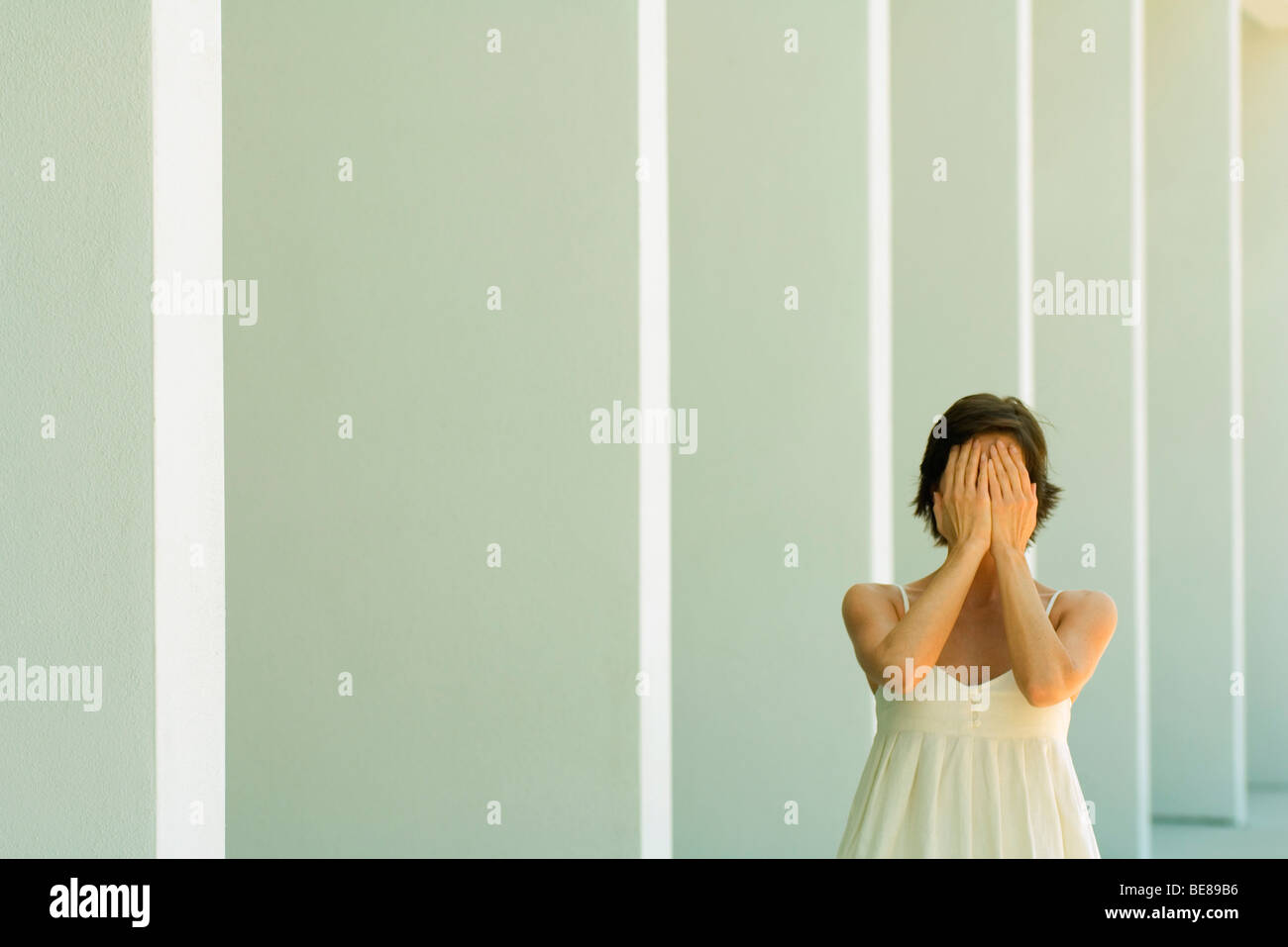 Donna che ricopre la faccia con le mani Foto Stock