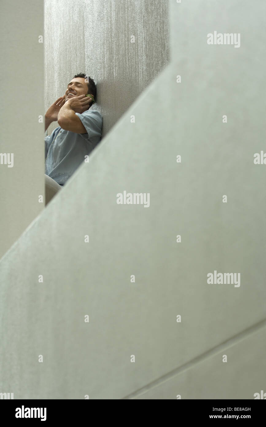 Uomo che ascolta le cuffie, sorridendo a basso angolo di visione Foto Stock