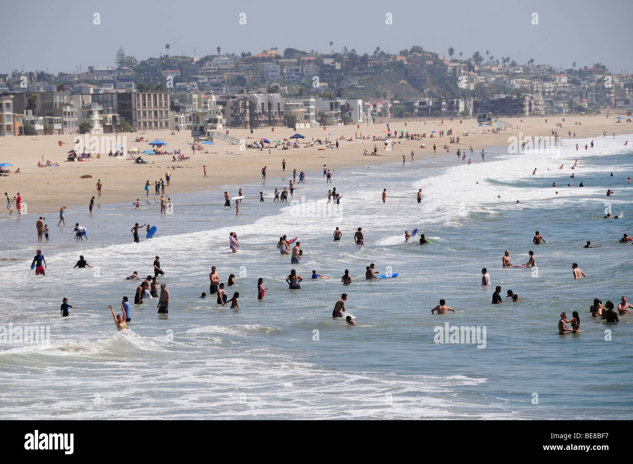 Stati Uniti, California, Los Angeles, Venice Beach surf e la spiaggia di sabbia in scena con la gente sulla spiaggia ed in mare con case spiaggia di rivestimento Foto Stock