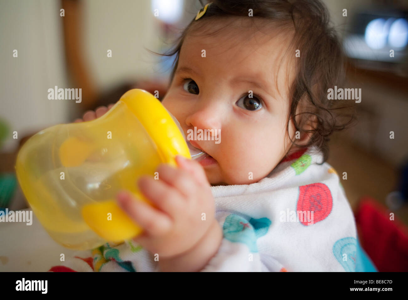 Baby girl prendendo il primo drink da un bicchiere Foto Stock
