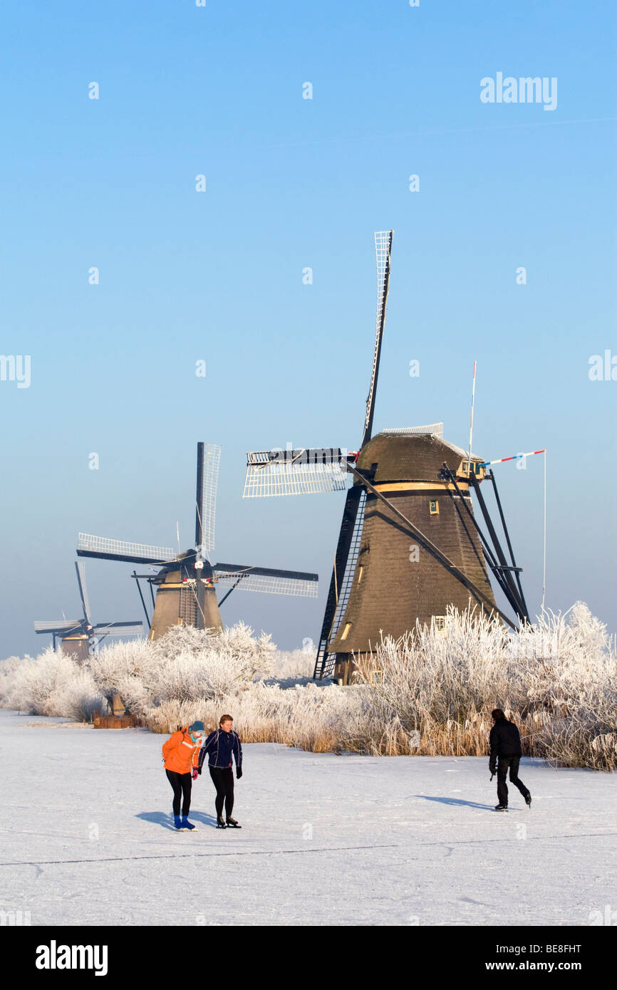 Schaatsers schaatsen langs de molens van Kinderdijk; pattinatori pattino lungo i mulini a vento di Kinderdijk Foto Stock