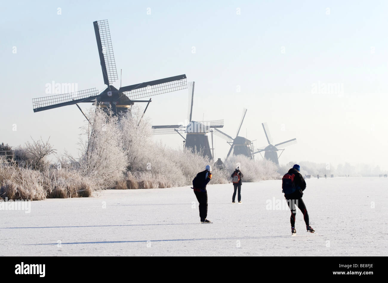 Schaatsers schaatsen langs de molens van Kinderdijk; pattinatori pattino lungo i mulini a vento di Kinderdijk Foto Stock