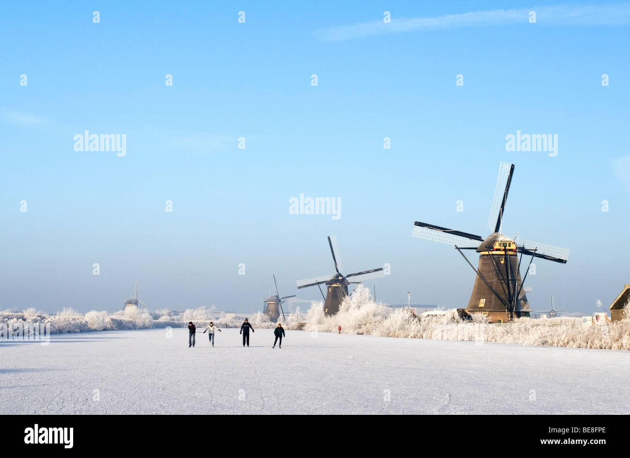 Schaatsers schaatsen langs de molens van Kinderdijk; pattinatori pattino lungo i mulini a vento di Kinderdijk Foto Stock