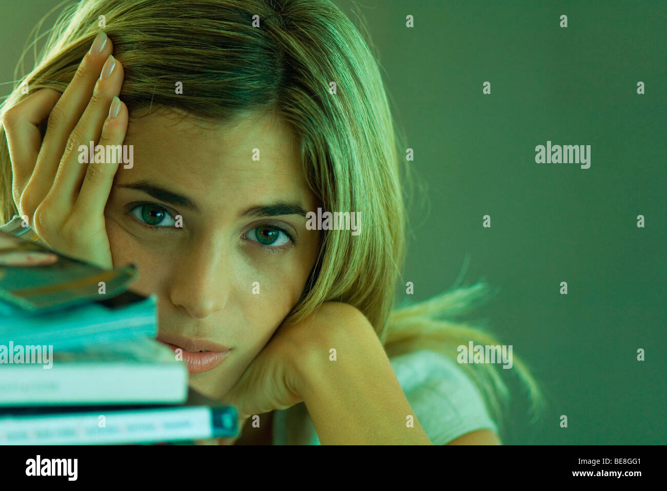Donna seduta con la pila di libri, cercando stancamente in telecamera Foto Stock