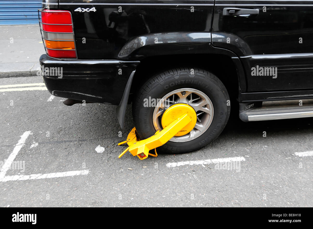 La polizia a morsetto di bloccaggio di ruota su una macchina parcheggiata in una zona di parcheggio, London, England, Regno Unito, Europa Foto Stock