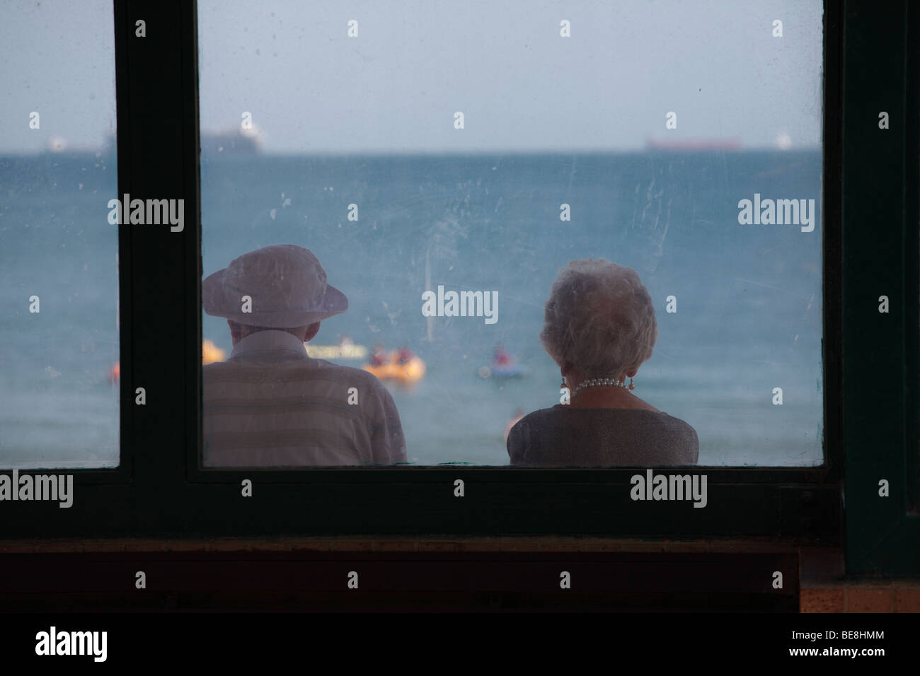 Vecchia coppia seduta che guarda al mare a navi Foto Stock