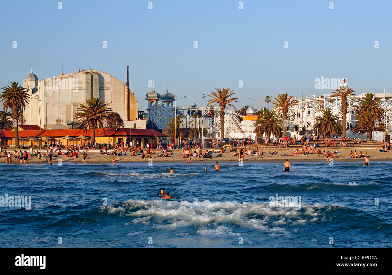 Australia, Victoria, Melbourne, St Kilda. La gente sulla spiaggia di St Kilda con il Palais Theatre e al Luna Park dietro. Foto Stock