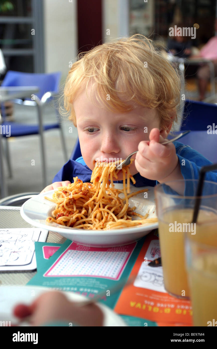 Ragazzo giovane mangiare spaghetti bolognese Foto Stock