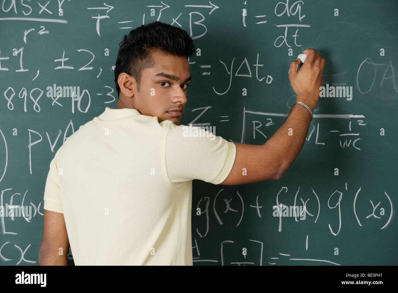 Giovane uomo scrivere formule su chalk board Foto Stock
