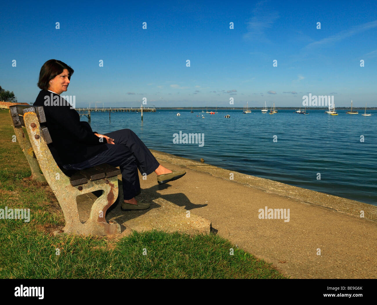 Donna che guarda al mare. Yarmouth, Isle of Wight, Inghilterra, Regno Unito. Foto Stock