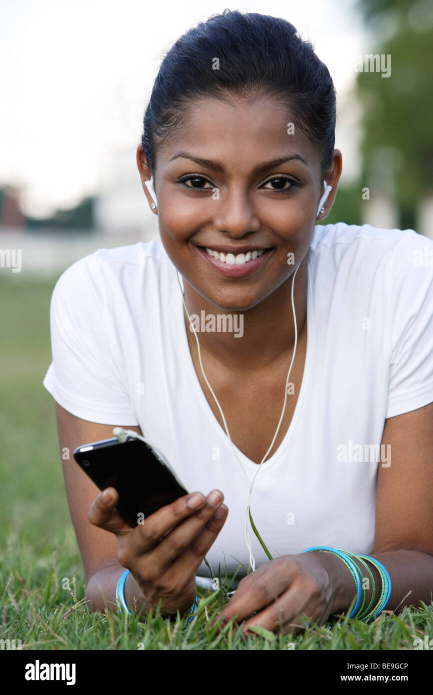 Giovane donna posa su erba ascoltando mp3 player Foto Stock