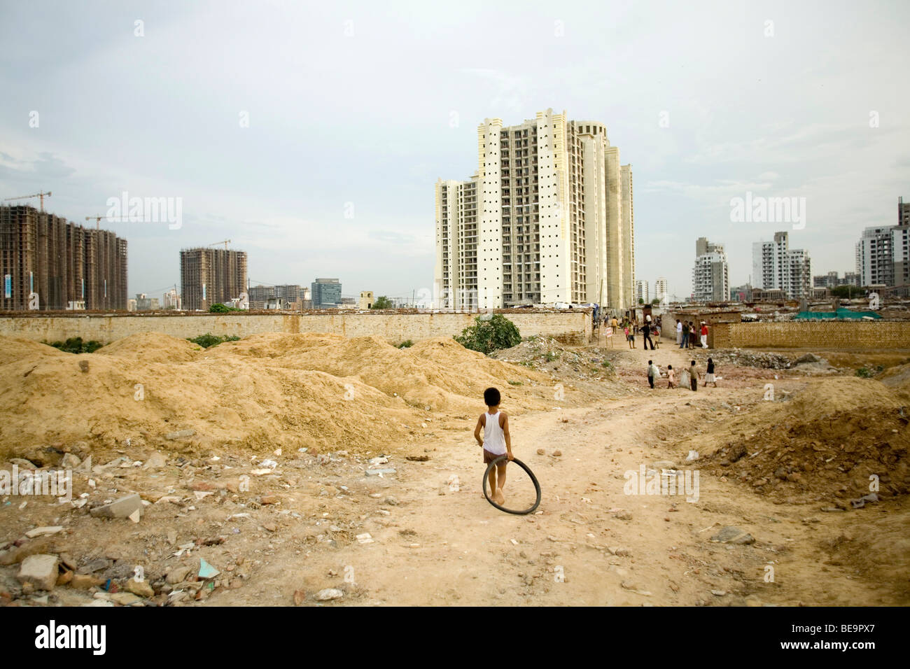 Un bambino da una lavoratori baraccopoli colonia che stanno costruendo una nuova station wagon, passeggiate a casa con una gomma in disuso pneumatico come un giocattolo in Gurgaon, Foto Stock