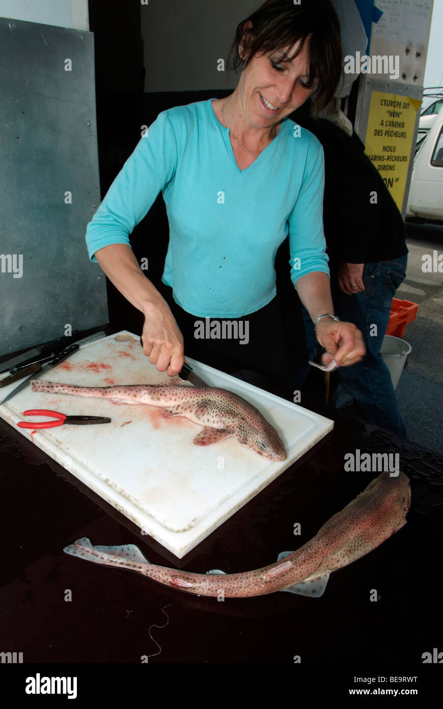 Sorridente pescivendolo il taglio di un pesce selvatico in un negozio nel porto di Boulogne Foto Stock