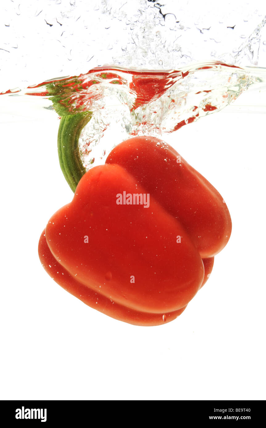 Peperone rosso è sceso in acqua isolata contro uno sfondo bianco Foto Stock