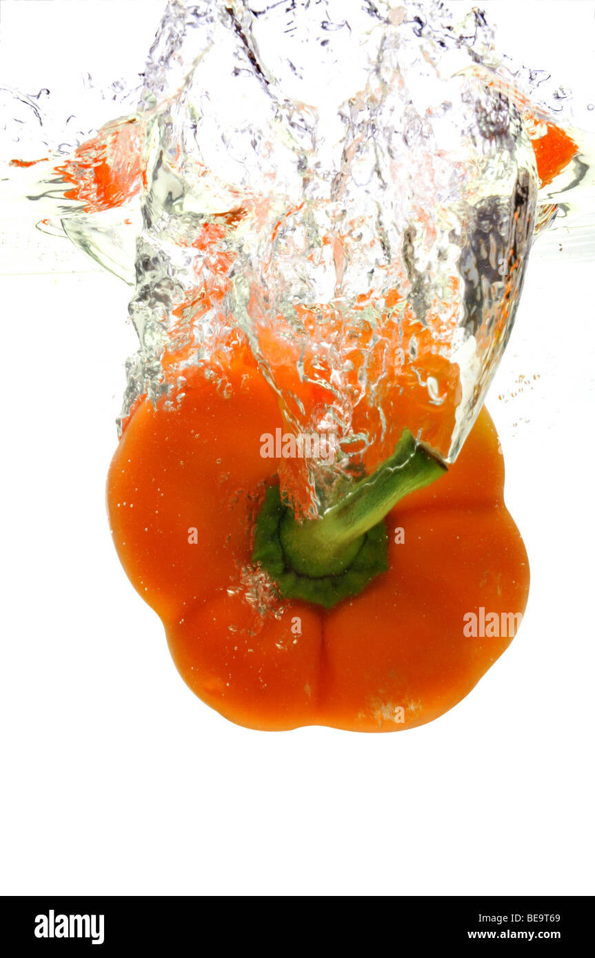 Arancio pepe è scesa in acqua isolate su uno sfondo bianco Foto Stock