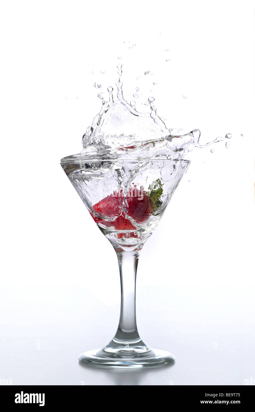 Fragola gocciolata in una coppetta Martini isolato su bianco Foto Stock