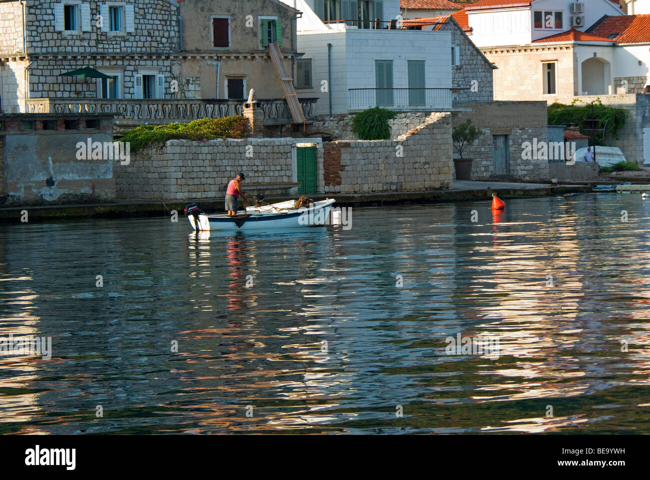 Croazia; Hrvartska; Kroatien, Croazia centrale, Kut, pescatore tira in rete in porto, di fronte a old town Foto Stock