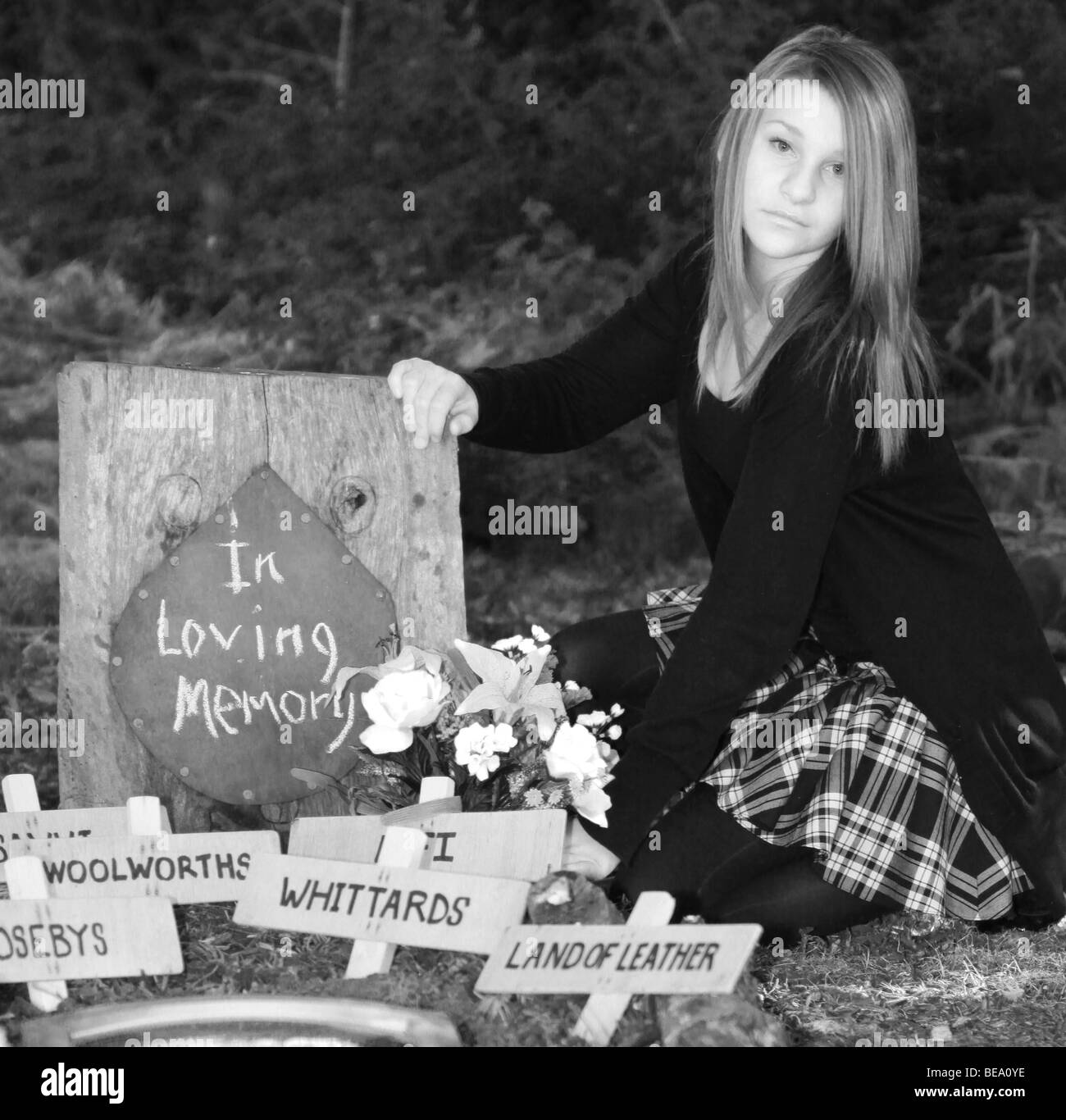 In lutto per i negozi - un mourner vestito in luoghi nero fiori sulla tomba per i negozi di Fairlands Valley Park Stevenage Foto Stock