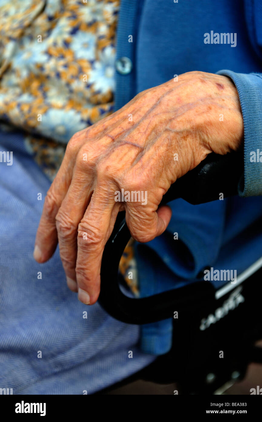 Stretta di mano donna anziana sul braccio della sedia a rotelle Foto Stock