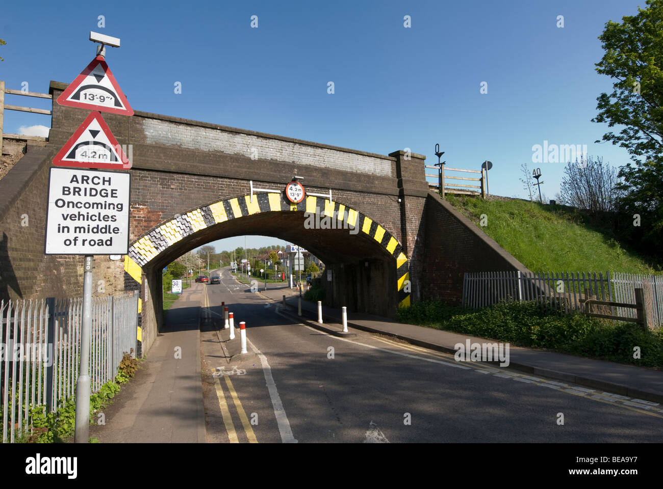 Indicazioni stradali per il traffico di guida unico file al di sotto di una altezza limitata ponte ferroviario in Inghilterra Foto Stock