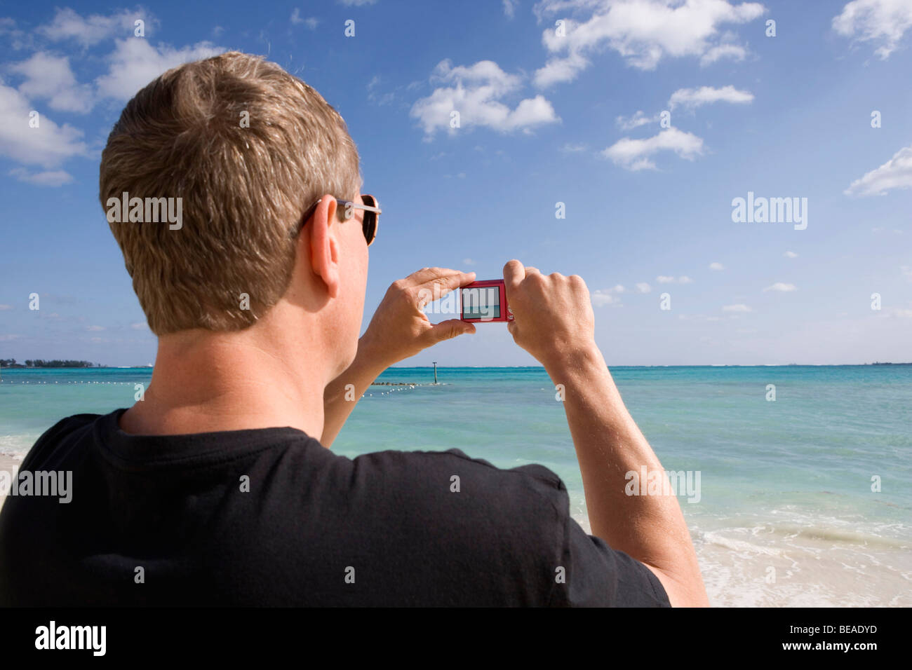 Vista posteriore di un uomo con una fotocamera digitale, Cable Beach, a Nassau, Bahamas, dei Caraibi Foto Stock