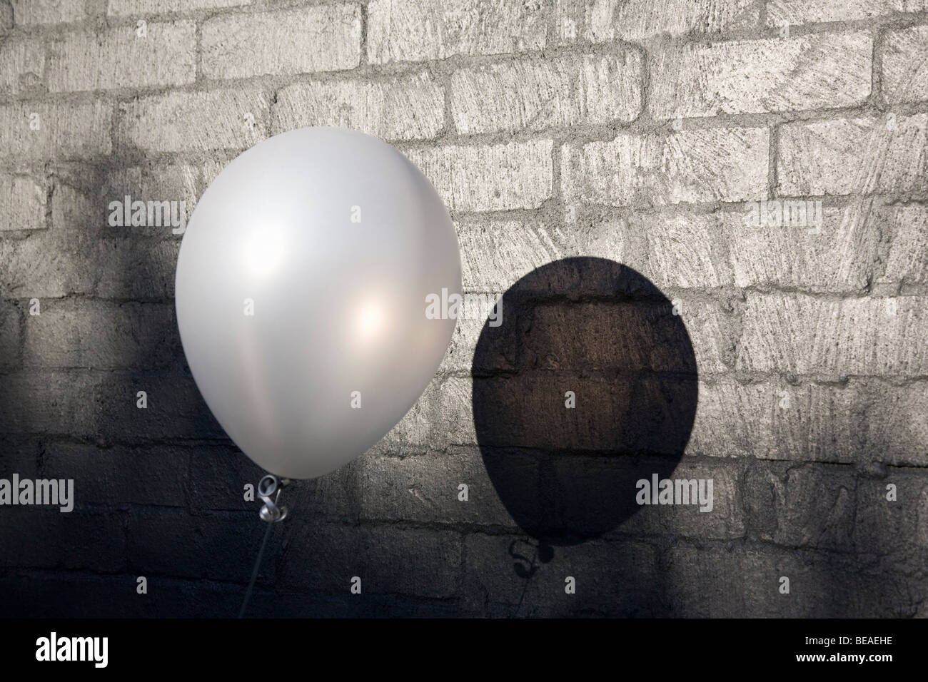 Un palloncino accanto a un muro di mattoni Foto Stock